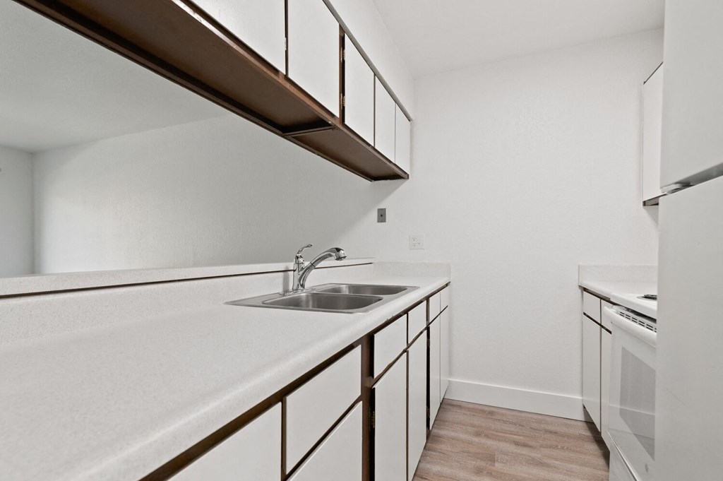 an empty kitchen with white counter tops and a sink