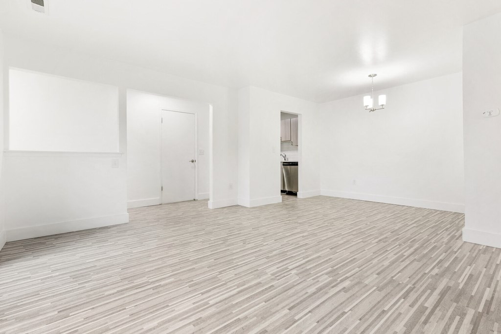 an empty living room with white walls and wood flooring