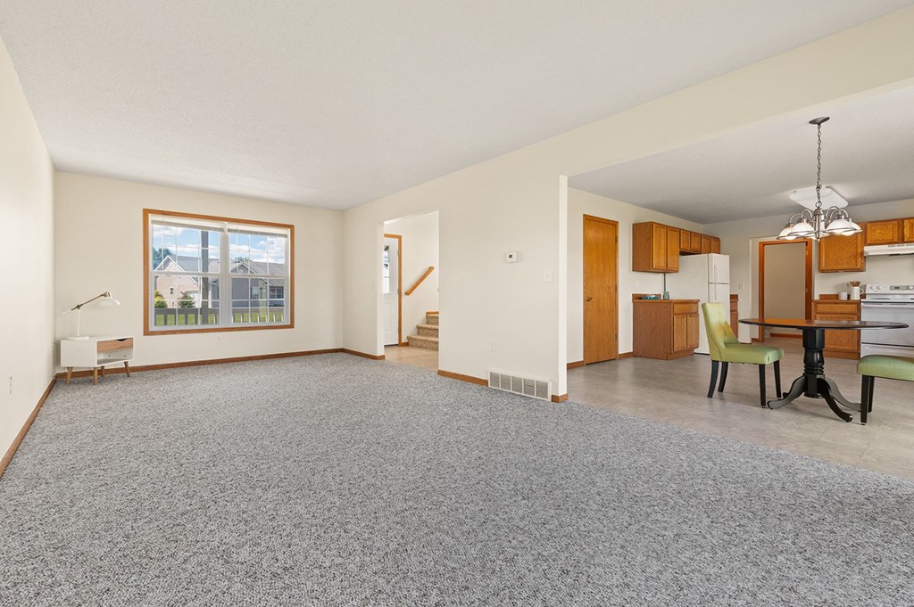 the living room and dining room of an apartment with a carpeted floor and a