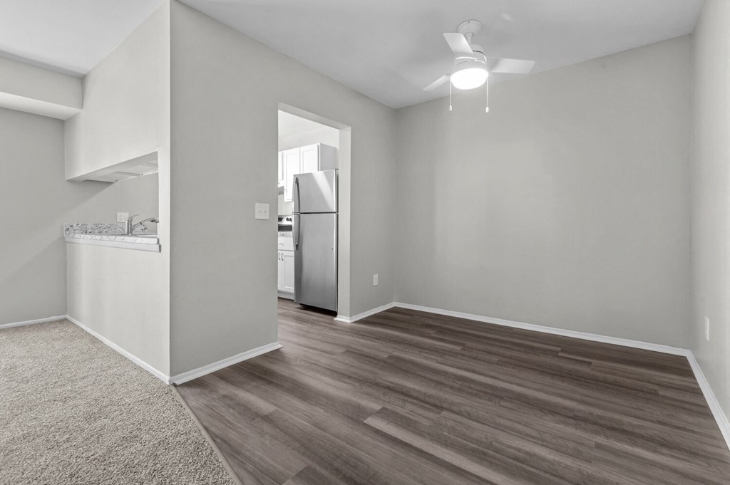 the living room and kitchen of an apartment with grey walls and wood flooring