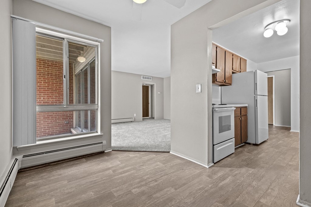 a living room with a large window and a kitchen in the background