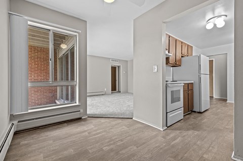a living room with a large window and a kitchen in the background