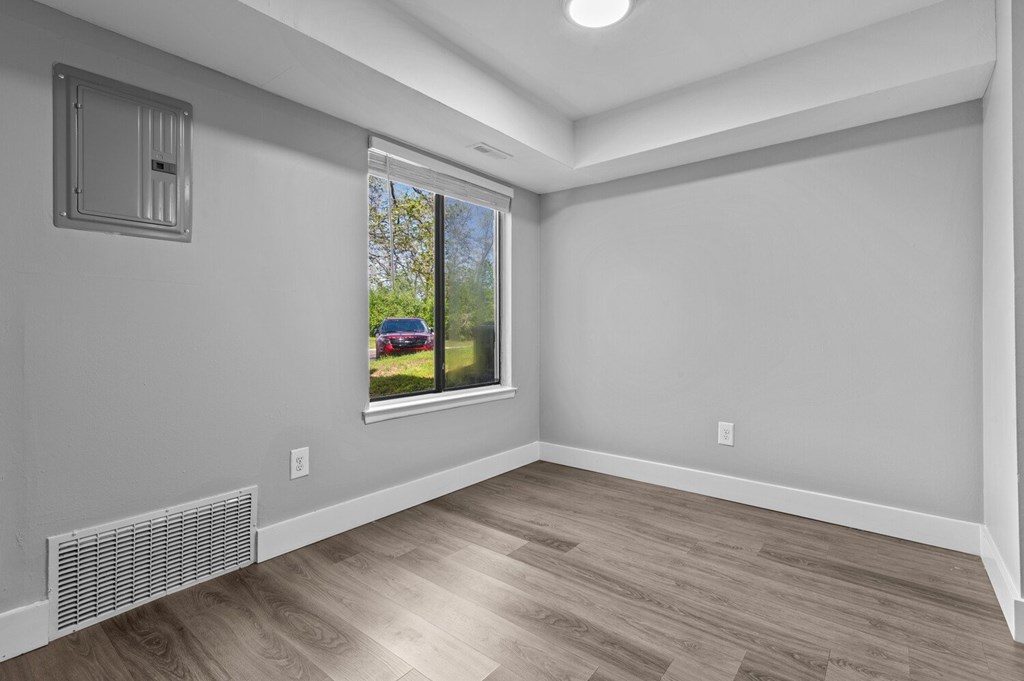 A room with a window showing a red car outside.