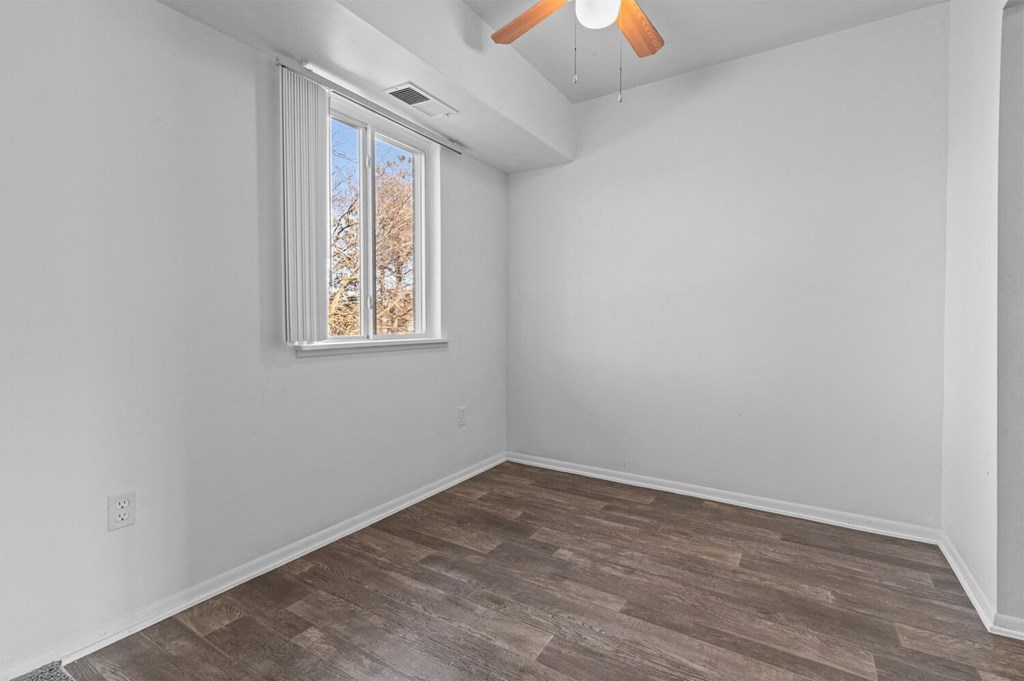 an empty room with wood flooring and a window