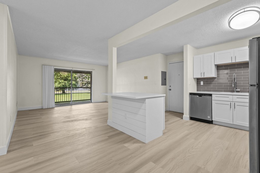 A kitchen with white cabinets and a wooden floor.