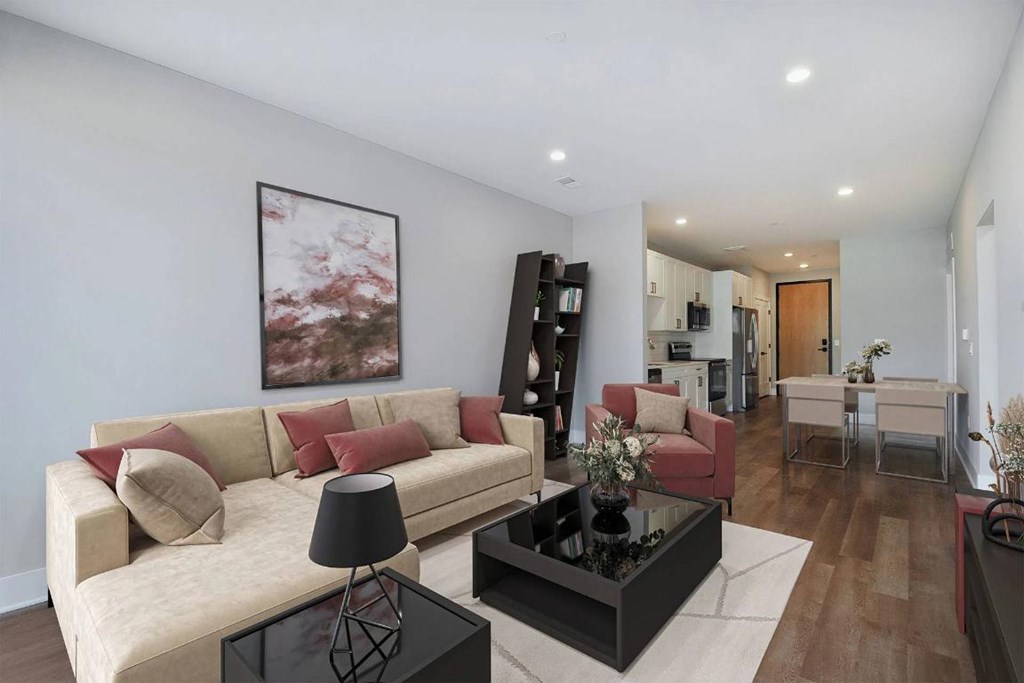 A living room with a beige couch, a black coffee table, and a painting on the wall.
