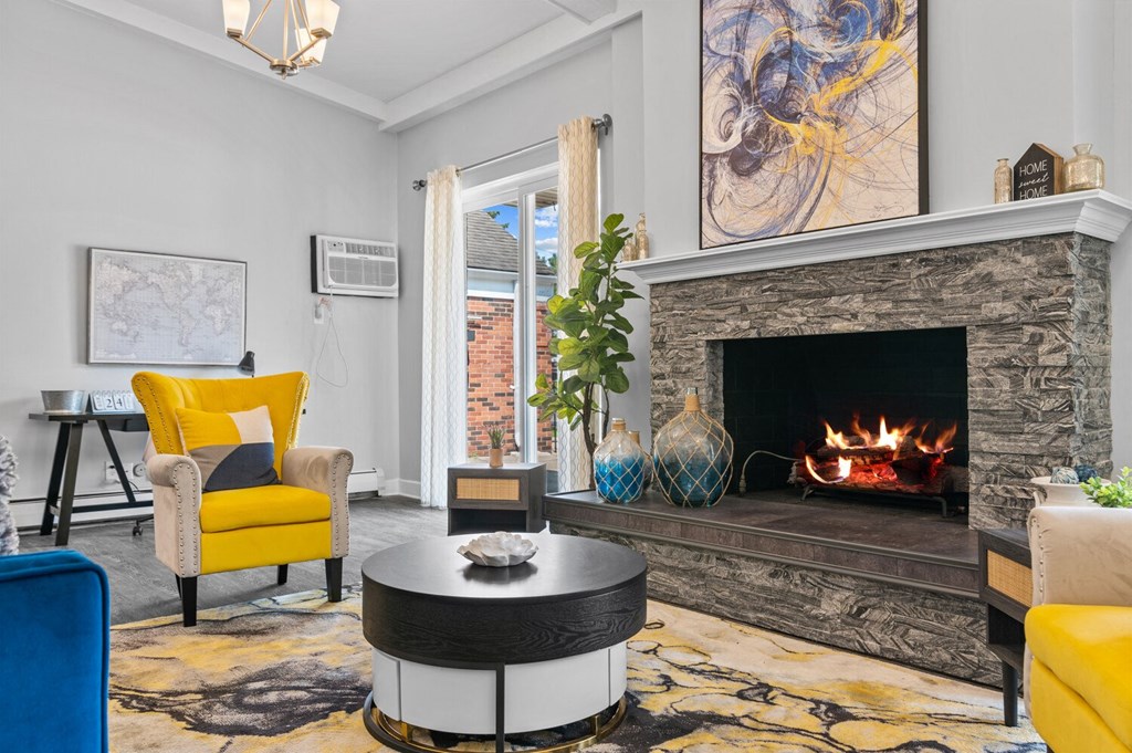 a living room with a fireplace and yellow chairs at Apple Ridge Apartments - Livonia, MI, Livonia, 48152