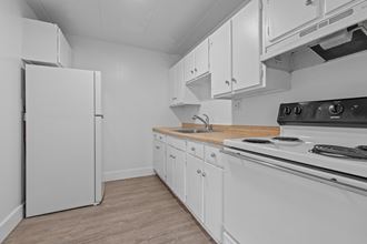 a kitchen with white cabinets and appliances and a white refrigerator
