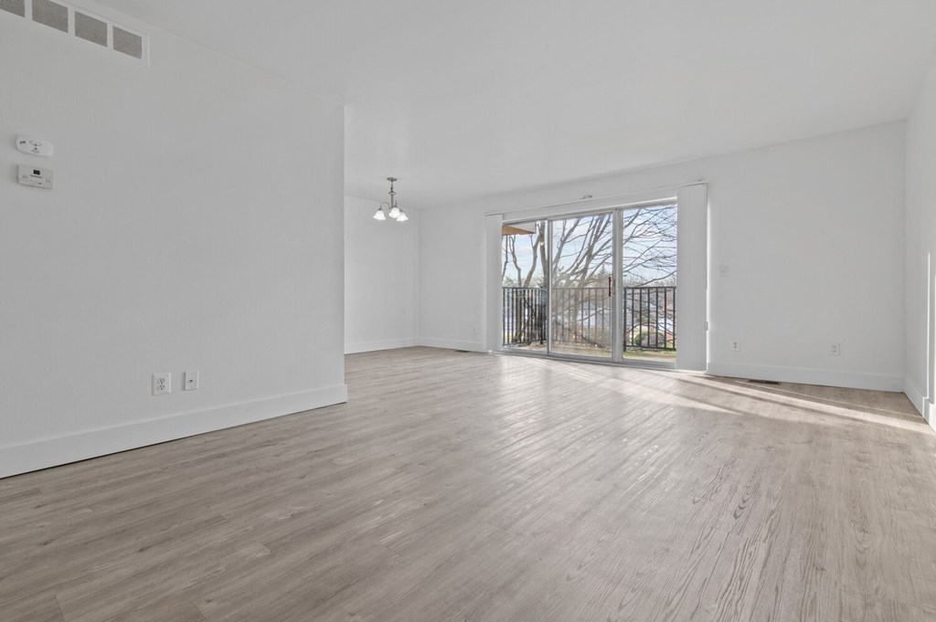 an empty living room with a sliding glass door to a balcony