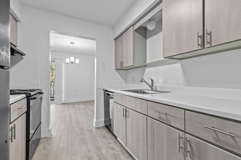 an empty kitchen with wood flooring and stainless steel appliances