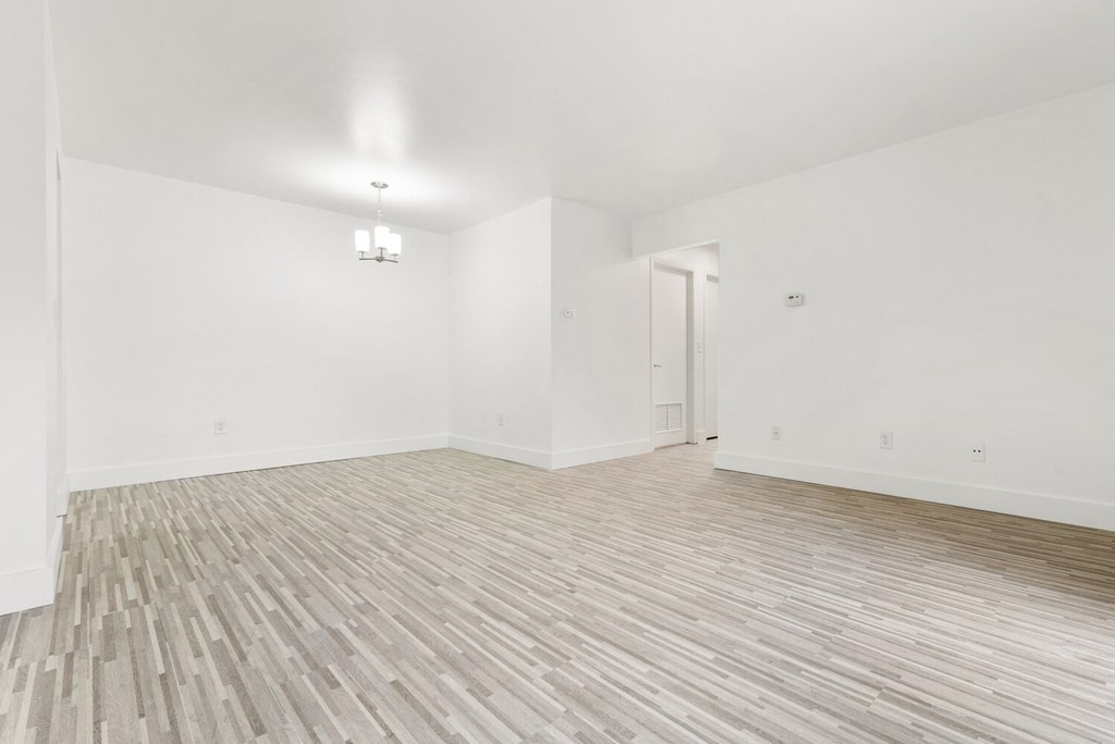 an empty living room with white walls and wood flooring