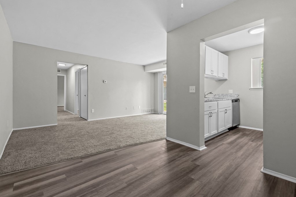 the living room and kitchen of a new home with white walls and wood floors