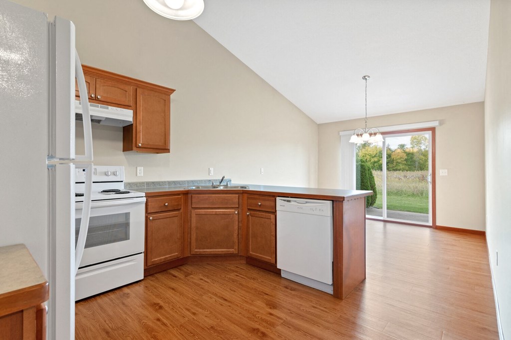 an empty kitchen with wooden cabinets and white appliances