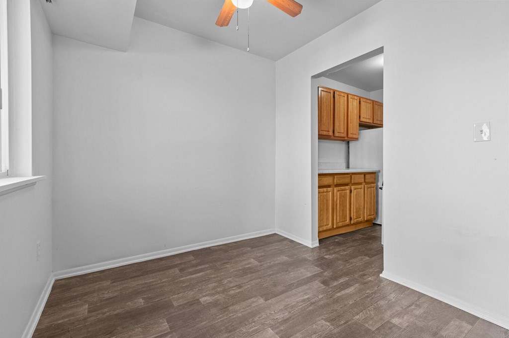 an empty living room and kitchen with wood flooring and white walls