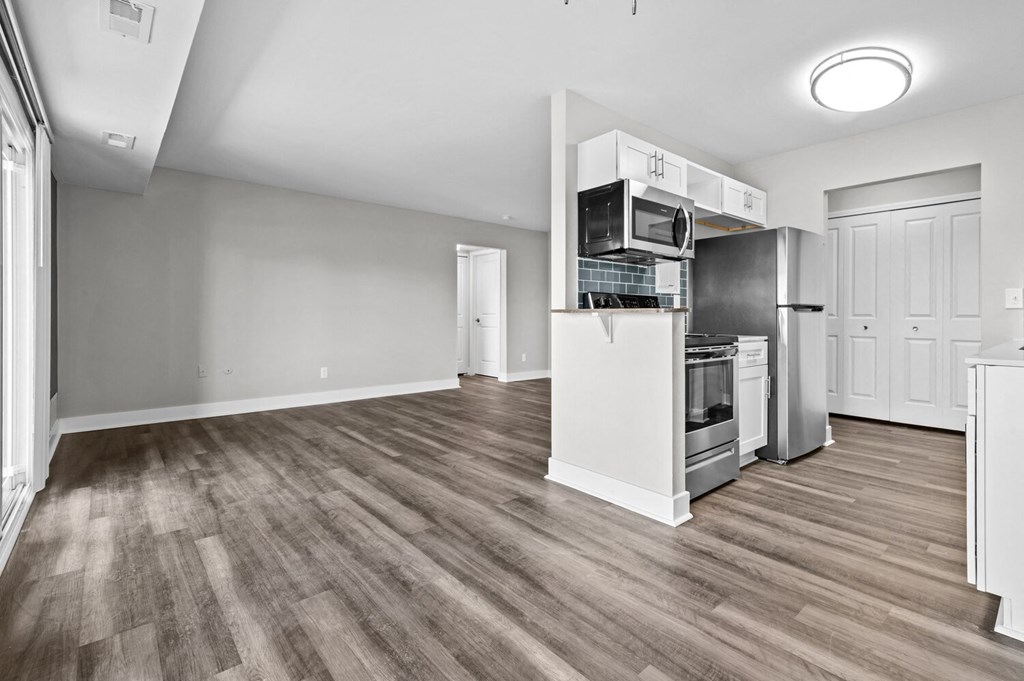 an empty living room with a kitchen with a stove and refrigerator at Sunnymede Apartments - Troy, MI, Troy, Michigan