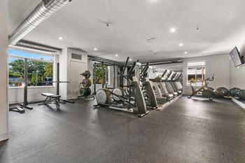 a gym with cardio equipment and a large window
