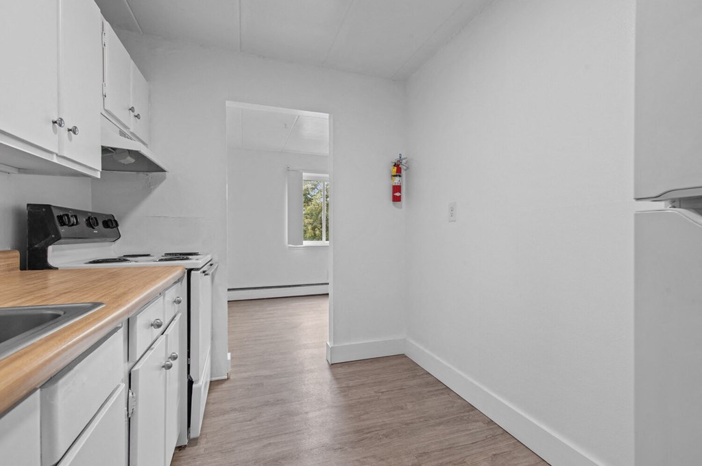 a kitchen with white cabinets and white appliances and a window