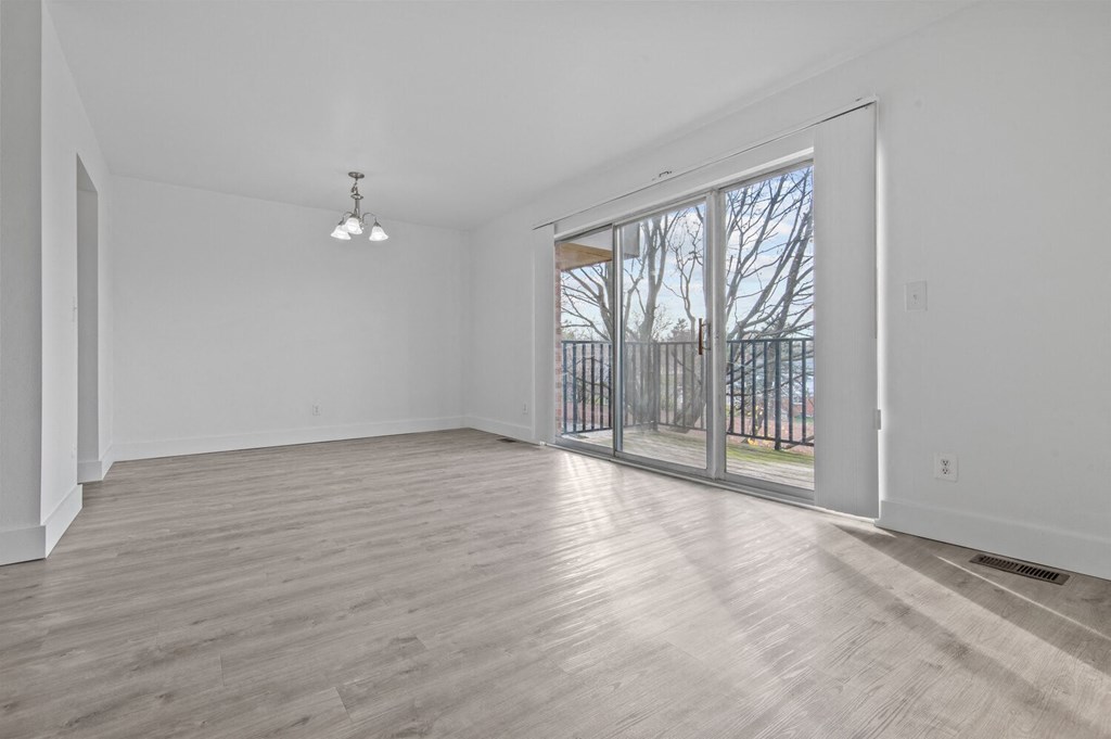 an empty living room with a sliding glass door to a balcony
