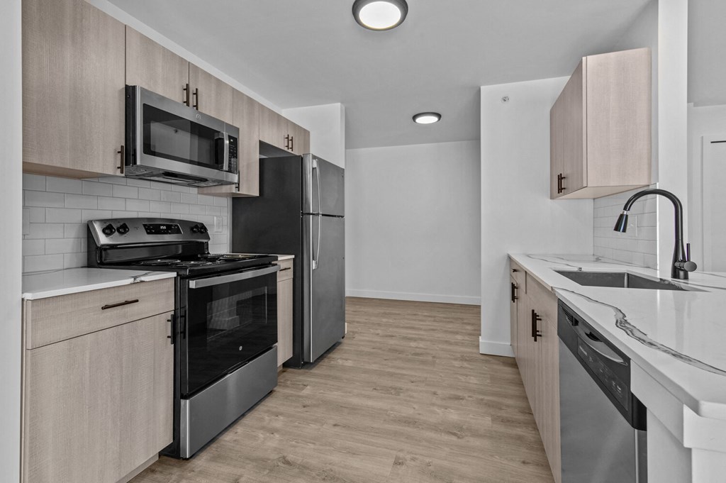 an empty kitchen with stainless steel appliances and wooden cabinets