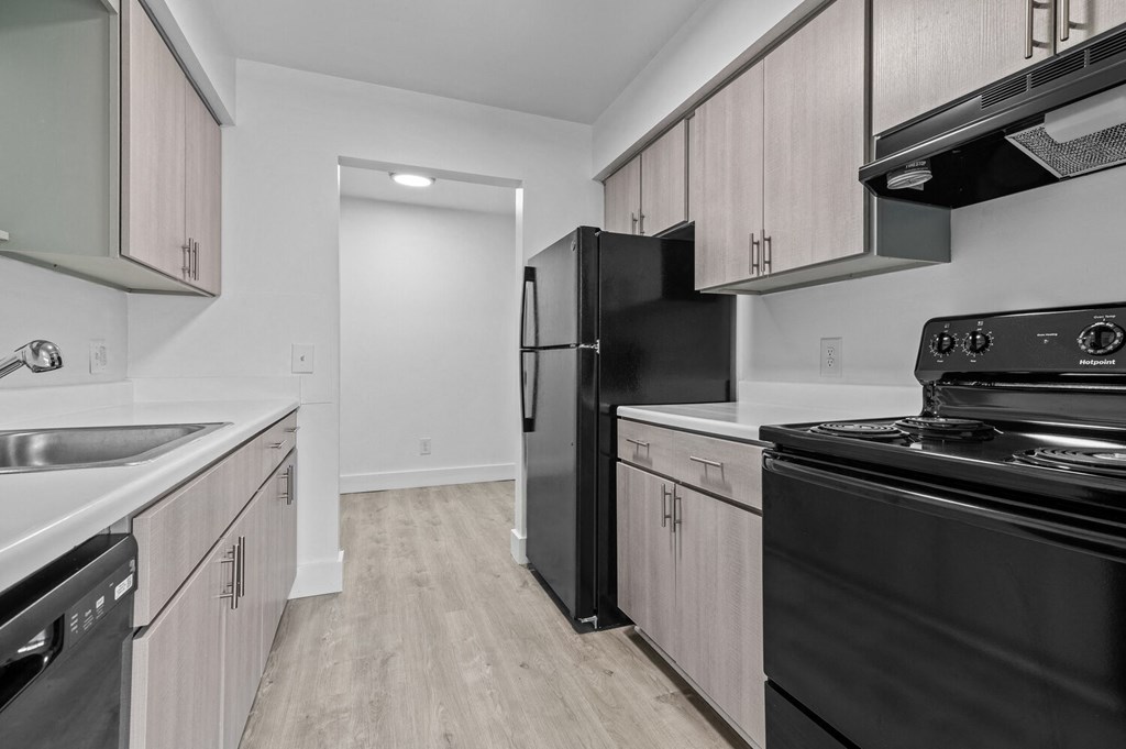 an empty kitchen with black appliances and white cabinets
