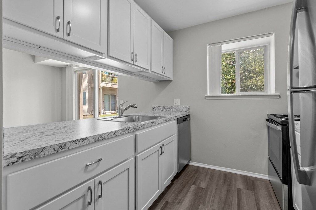 an empty kitchen with white cabinets and stainless steel appliances