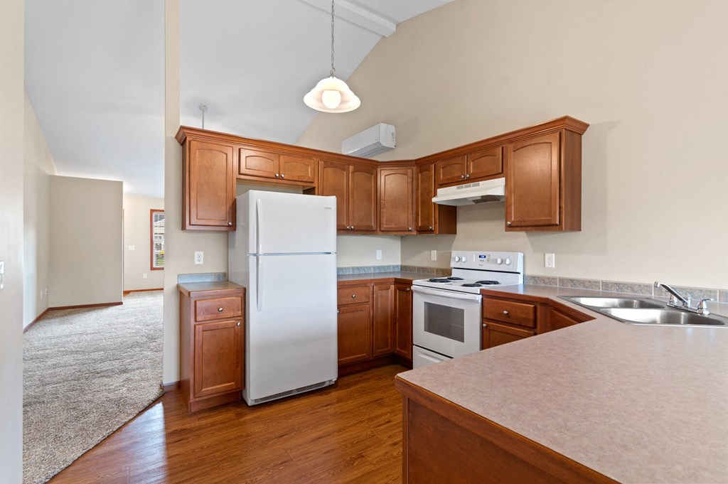 an empty kitchen with wooden cabinets and a white refrigerator