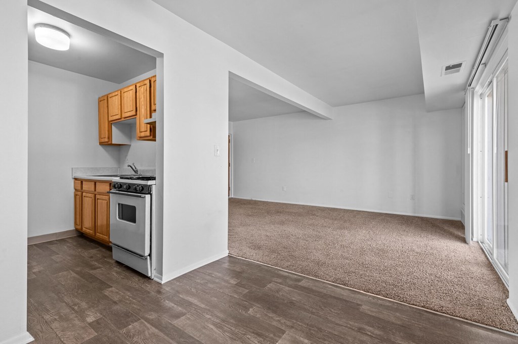the kitchen and living room of an empty house with white walls and wood flooring