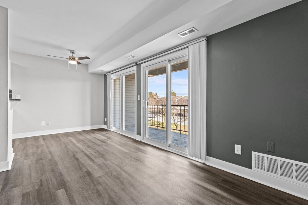 an empty living room with sliding glass doors to a balcony at Sunnymede Apartments - Troy, MI, Troy
