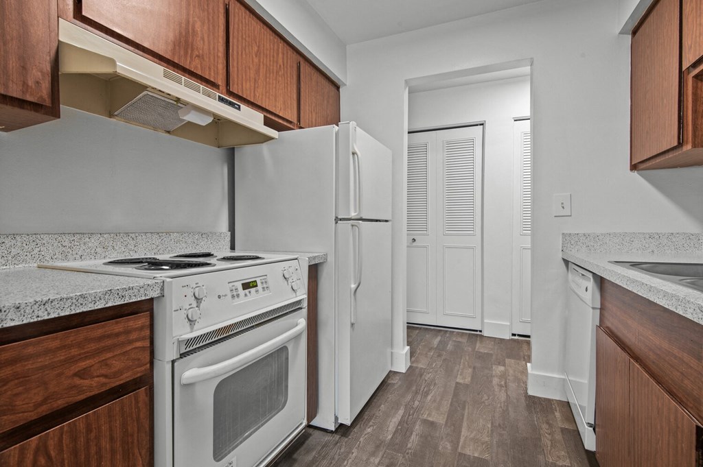 a kitchen with white appliances and wooden cabinets and a refrigerator