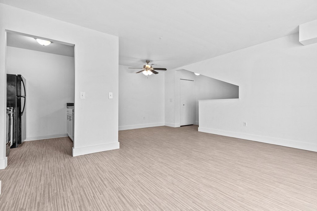 a living room with white walls and a ceiling fan