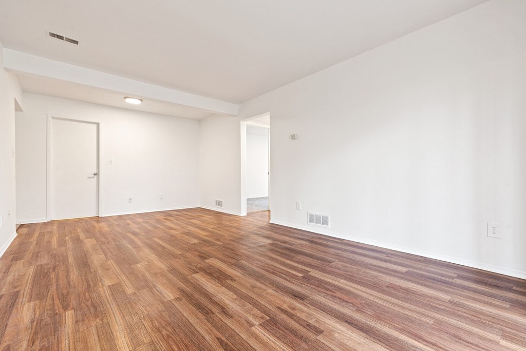 an empty living room with wood flooring and white walls