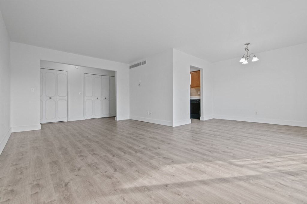 an empty living room with white walls and wood flooring