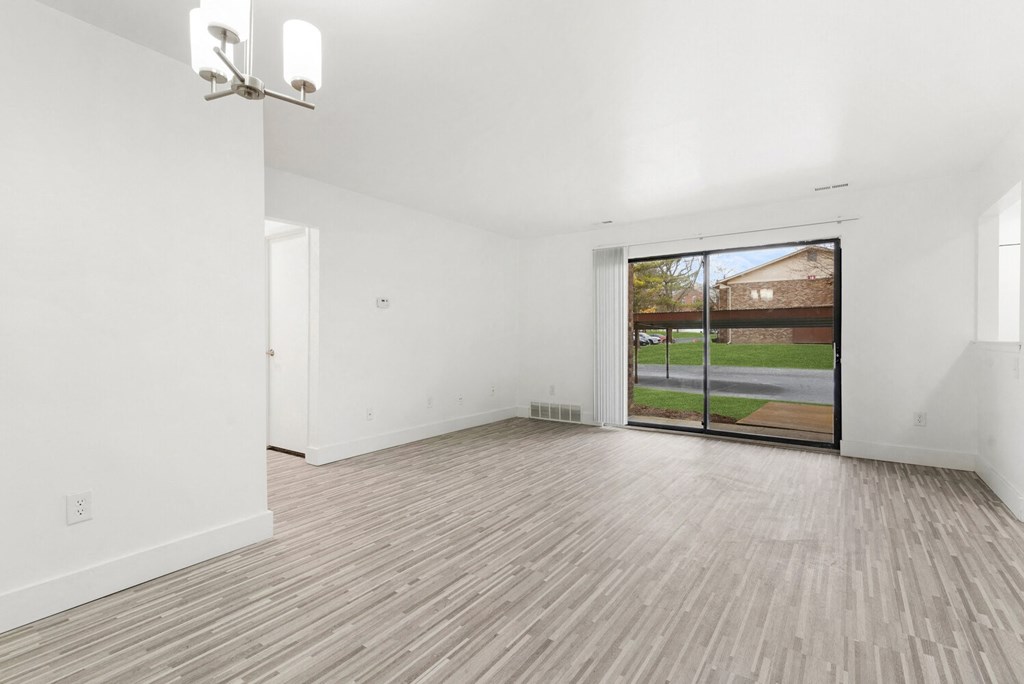 an empty living room with white walls and a sliding glass door