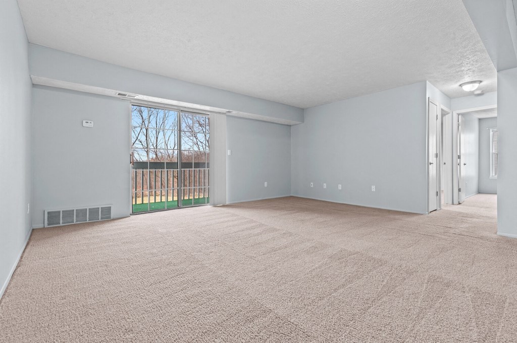 an empty living room with a sliding glass door to a balcony  at Fairfax Apartments - Lansing, MI, Michigan