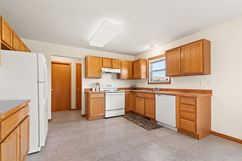a kitchen with white appliances and wooden cabinets