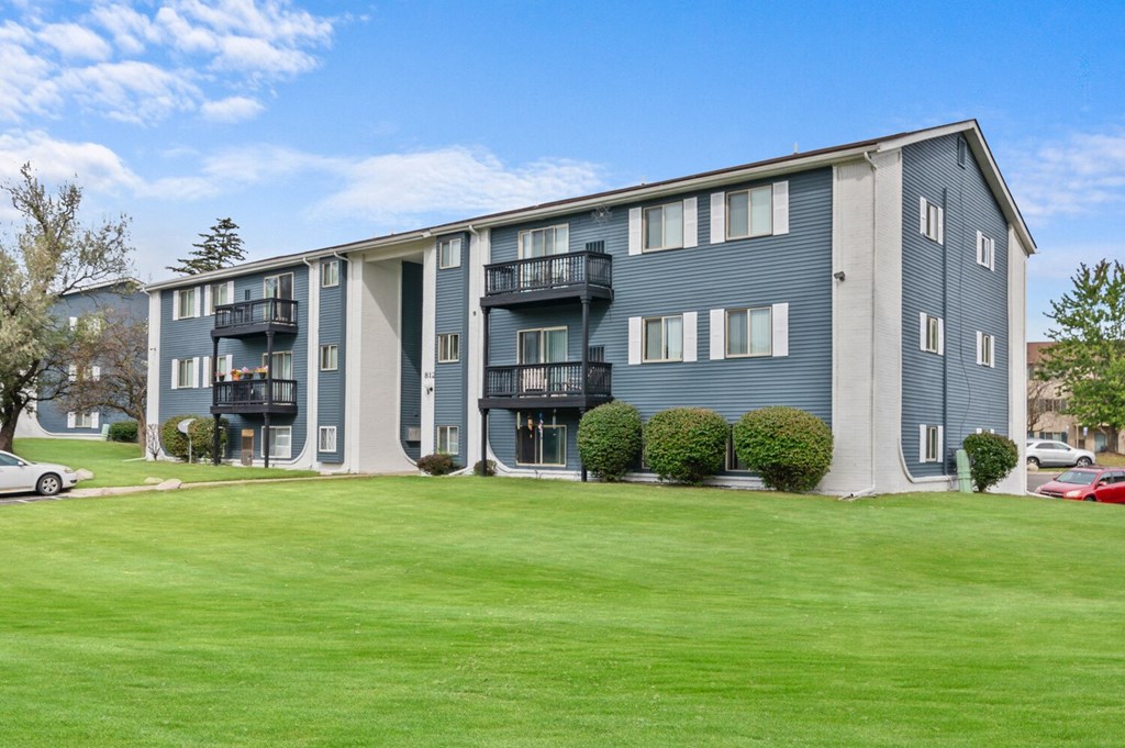 an apartment building with a green lawn in front of it