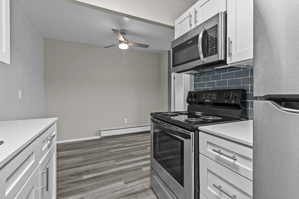 a kitchen with white cabinets and black appliances and a ceiling fan