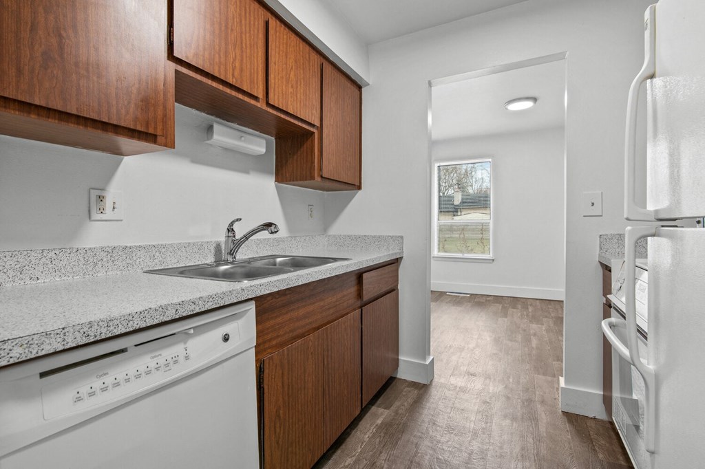 an empty kitchen with white appliances and wood cabinets