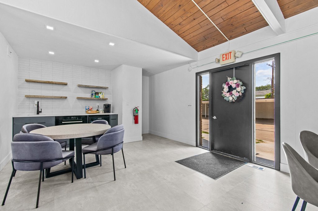 a dining area with a table and chairs and a door with a wreath on it