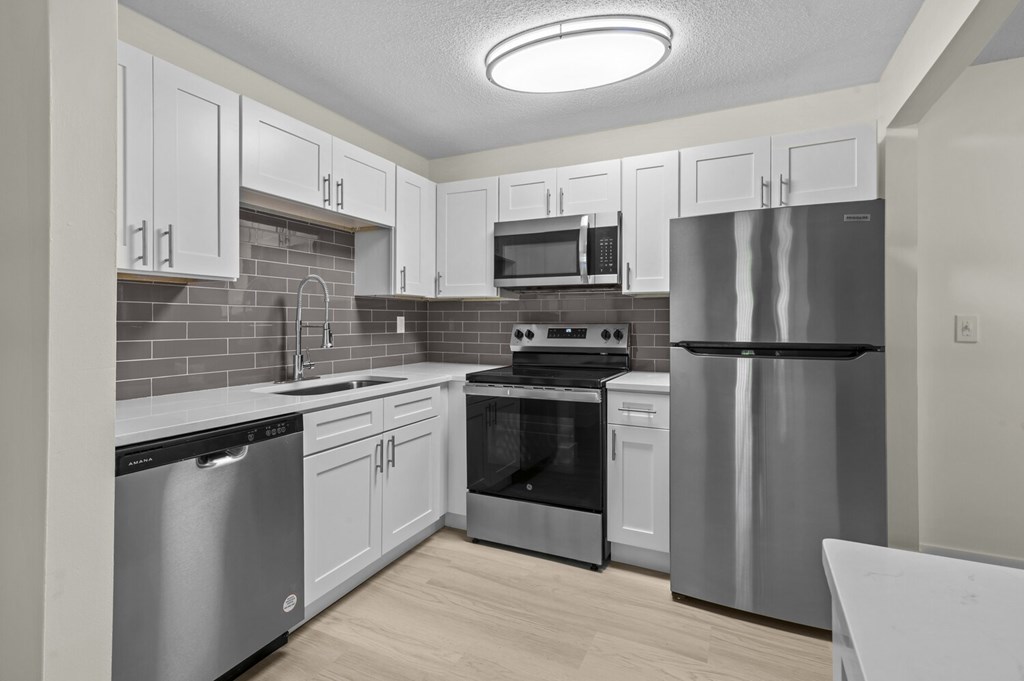 A kitchen with stainless steel appliances and white cabinets.