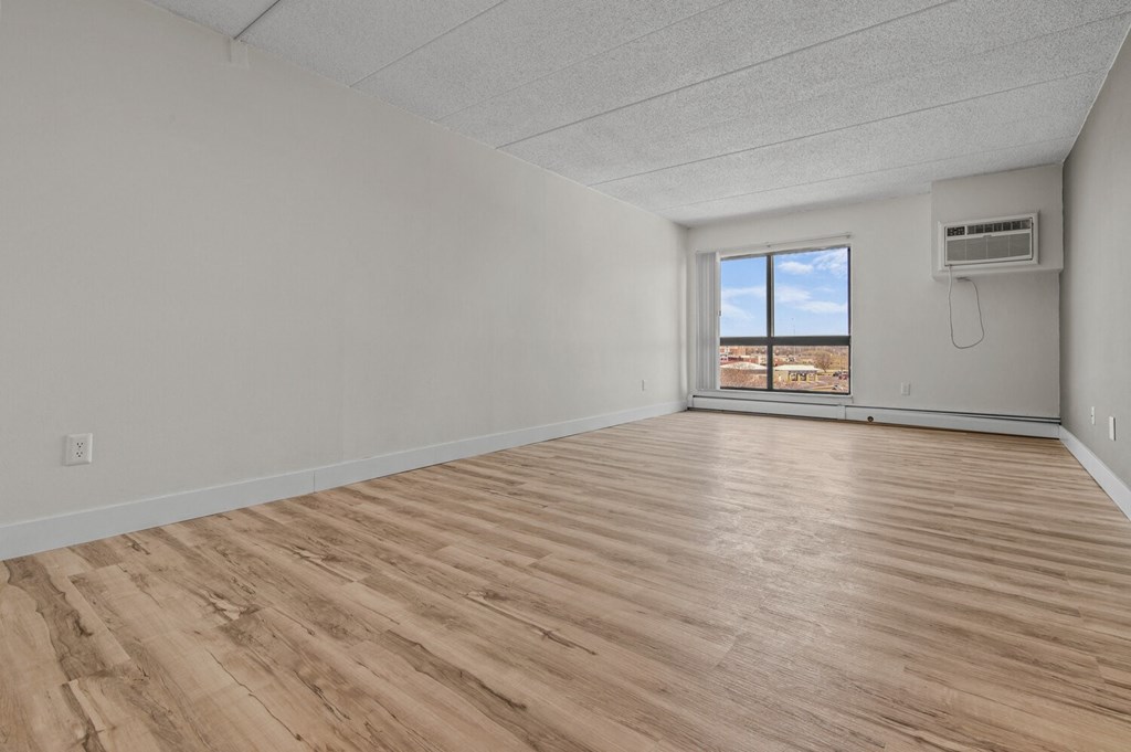 an empty living room with wood flooring and a window