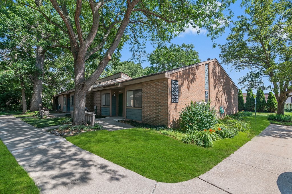 the front of a brick building with trees and a sidewalk