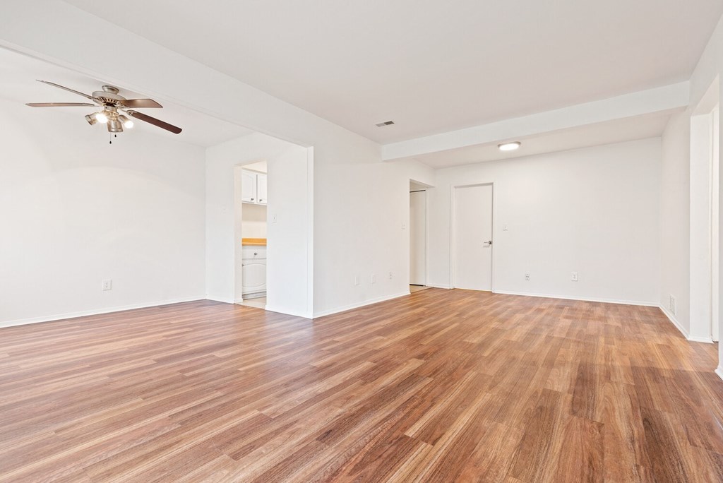 an empty living room with a ceiling fan and wood flooring