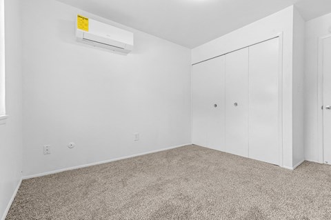 a bedroom with white walls and carpet and white closets