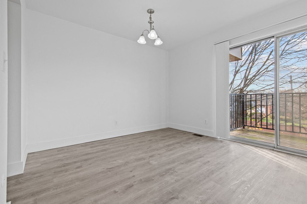 an empty living room with a sliding glass door to a balcony