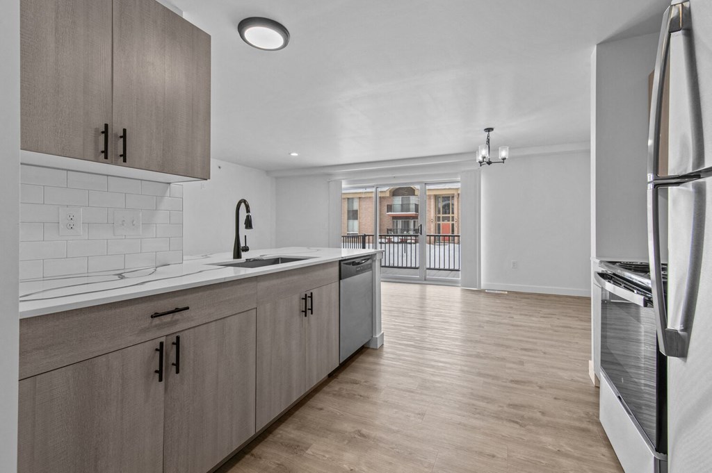 an open kitchen with wooden cabinets and a view of a living room