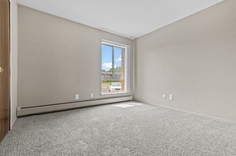 a bedroom with a large window and carpet