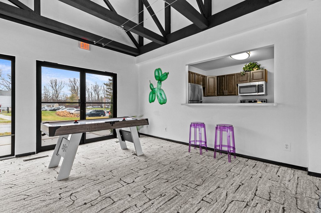 a games room with a ping pong table and a kitchen