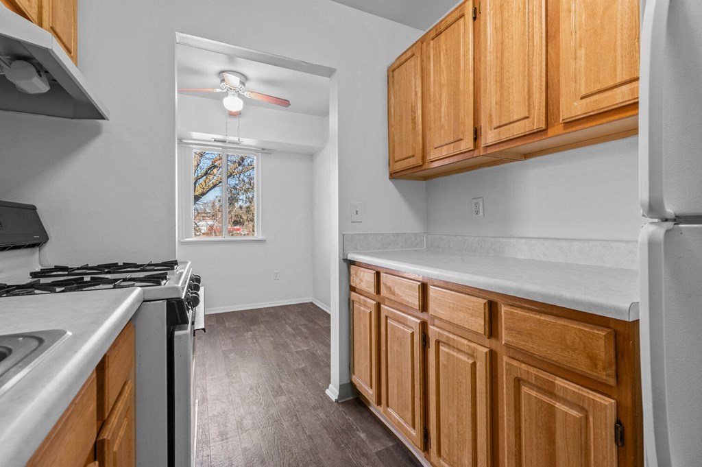 a kitchen with wood cabinets and white counter tops and a stove and refrigerator