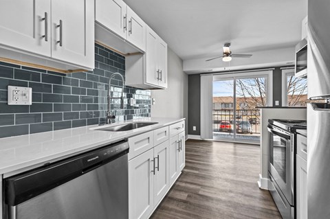 a kitchen with white cabinets and stainless steel appliances and a window